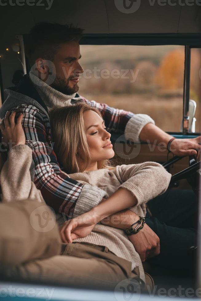 Nothing else but love. Attractive young woman resting and smiling while her boyfriend driving retro style mini van photo