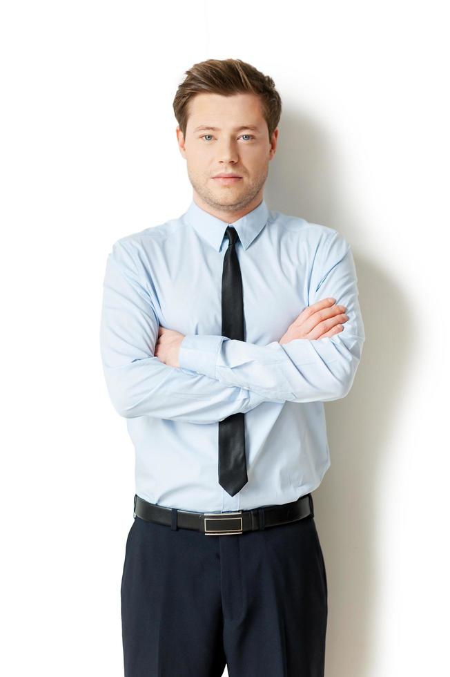 Young and successful. Confident young man in formalwear looking at camera and keeping arms crossed while standing isolated on white photo