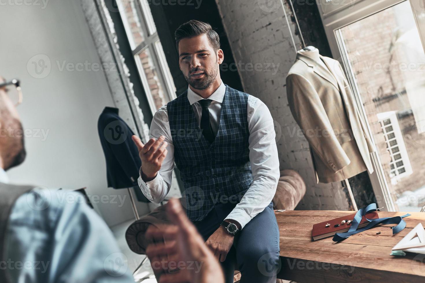 Long working day. Two young fashionable men having a discussion while spending time in the workshop photo