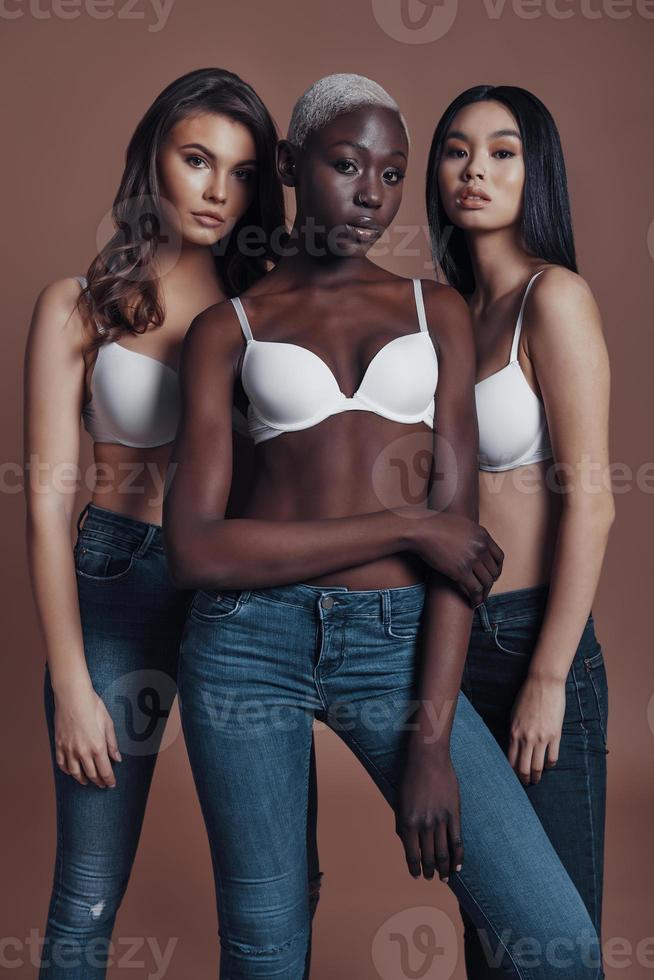 Free your individuality Three attractive young women looking at camera while standing against brown background photo