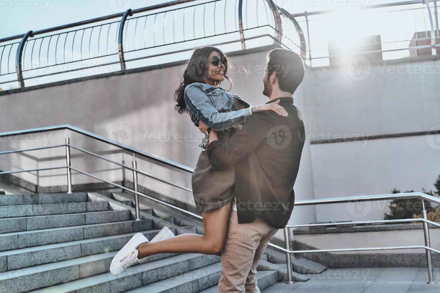 Falling in love. Handsome man carrying young attractive woman while spending time outdoors photo