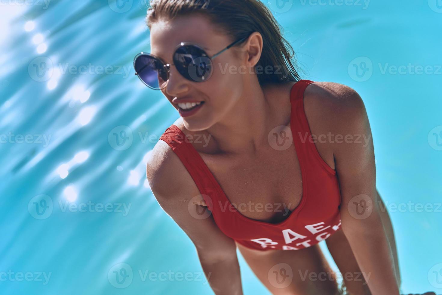 Gorgeous beauty. Top view of attractive young woman in swimwear smiling while getting out the swimming pool photo