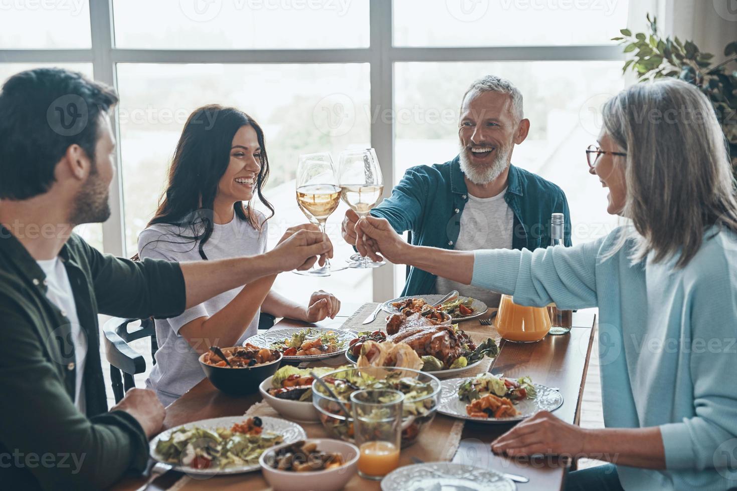 Happy multi-generation family toasting each other and smiling while having dinner together photo