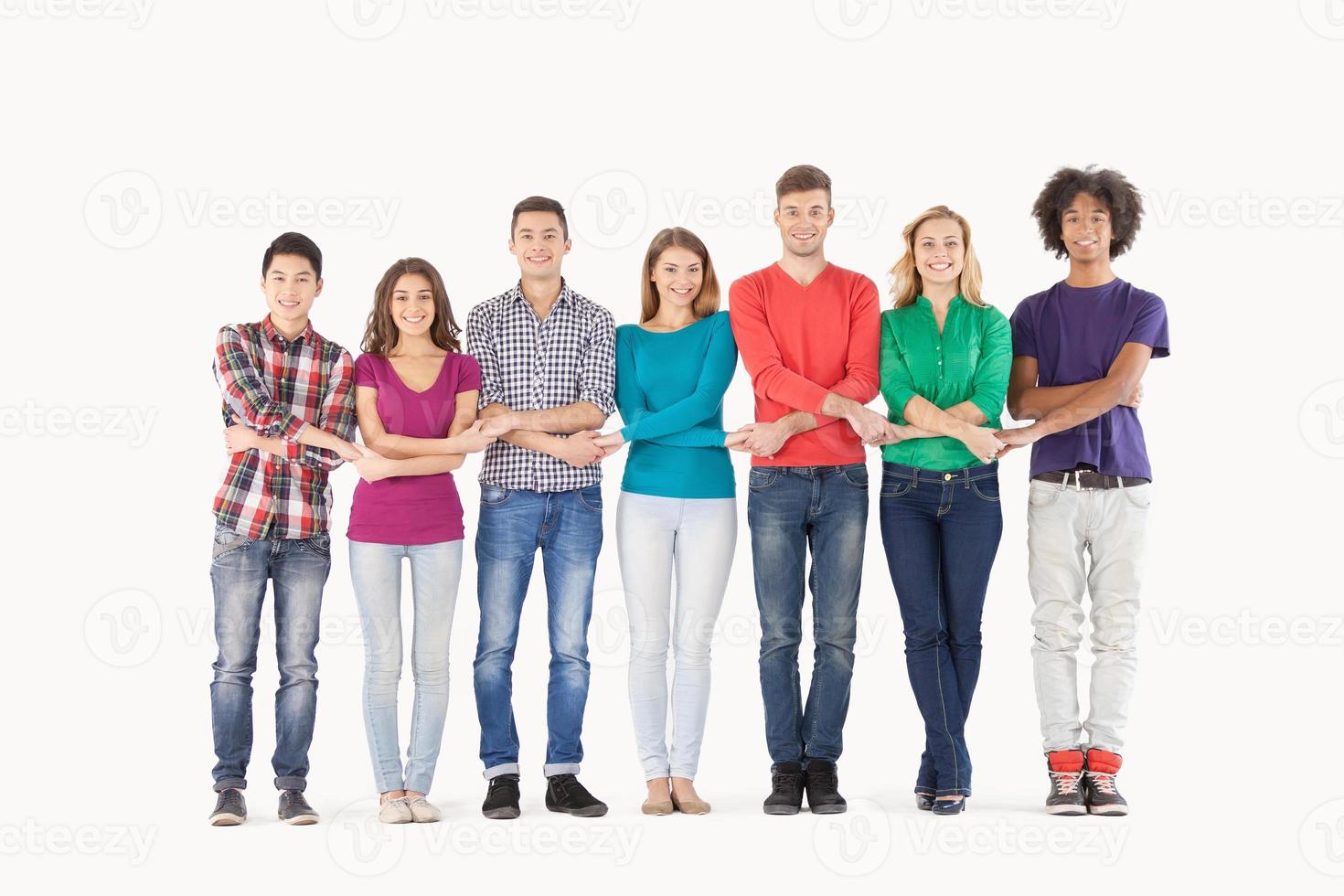 Together we are strong. Full length of cheerful multi-ethnic people holding hands while standing in a row photo