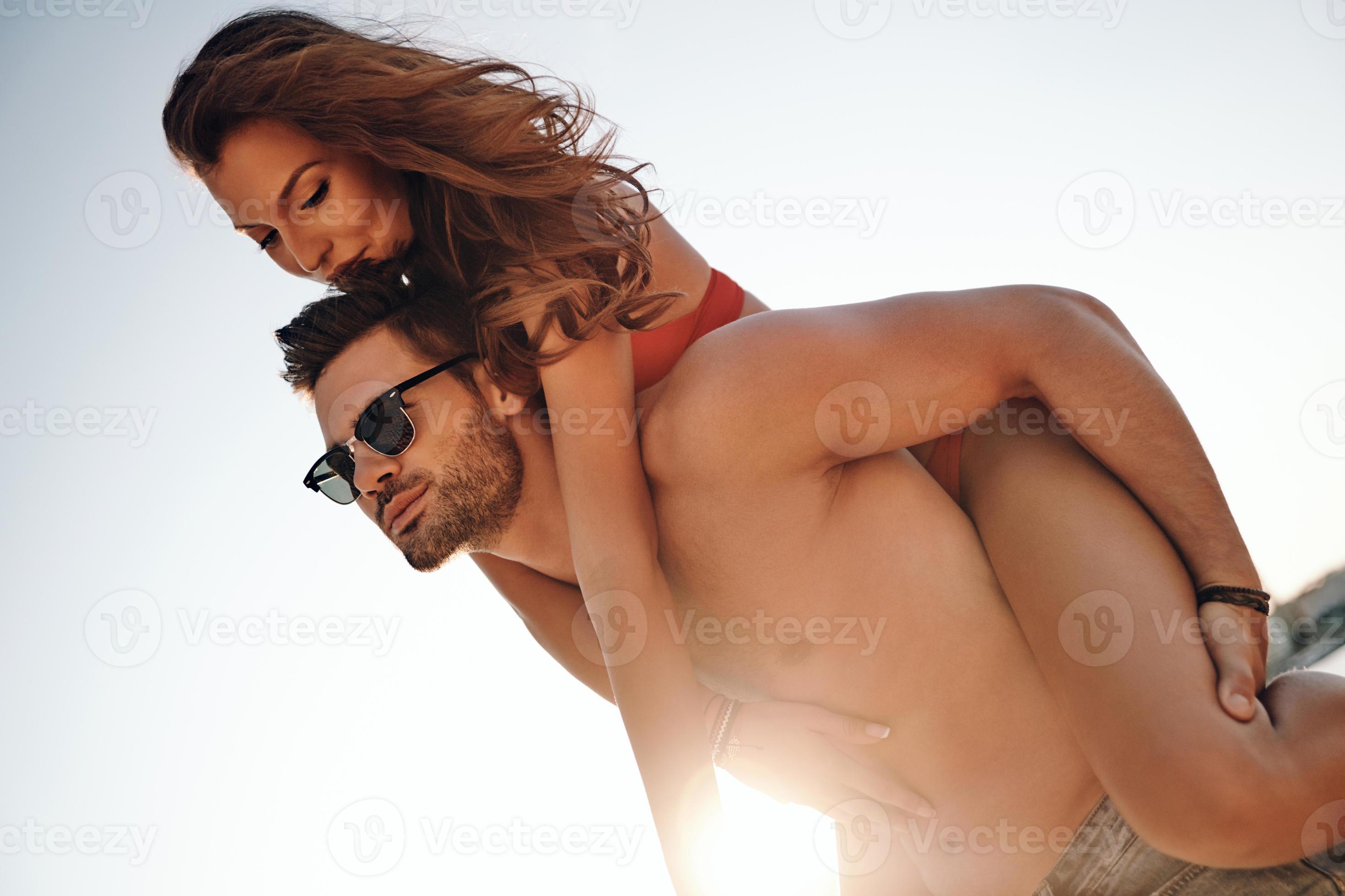 Handsome young man giving his attractive girlfriend a piggy back ride while spending carefree time on the beach 13538177 Stock Photo at Vecteezy picture