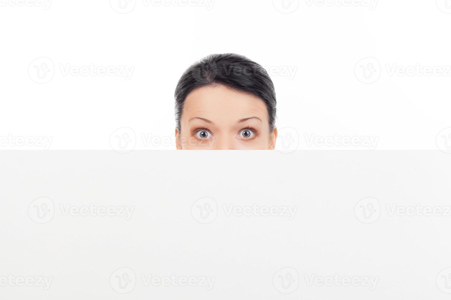Looking out of copy space. Shocked young woman looking out of copy space while isolated on white photo