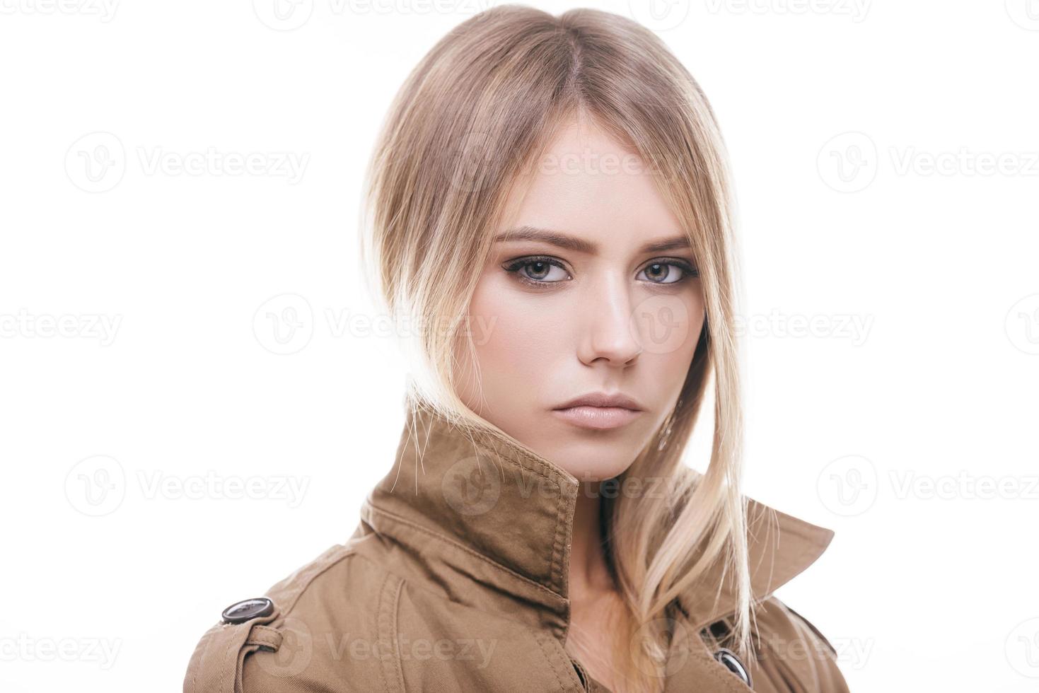 belleza otoñal. retrato de una joven atractiva con abrigo mirando a la cámara mientras se enfrenta a un fondo blanco foto