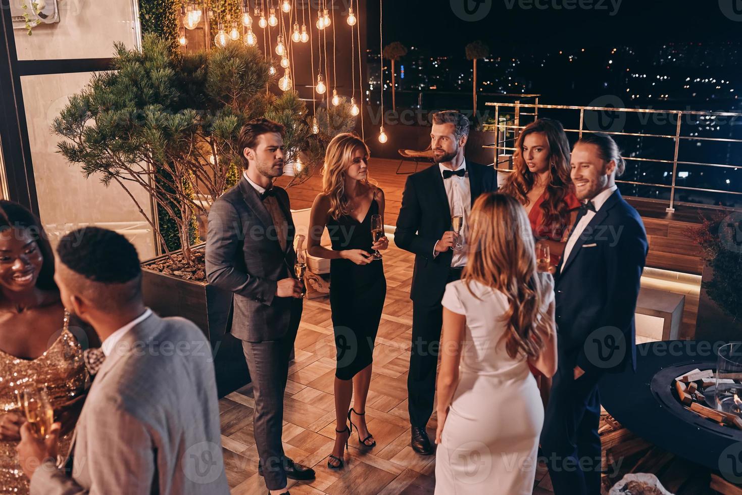 Group of people in formalwear communicating and smiling while spending time on luxury party photo