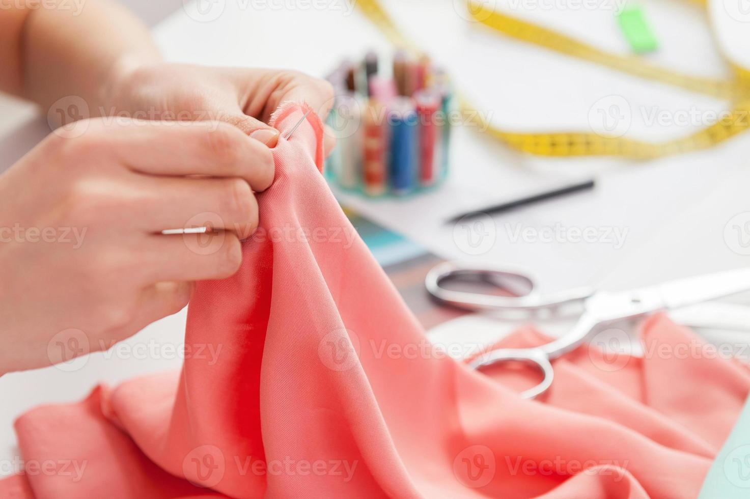 Tailor sewing. Cropped image of tailor sewing while sitting at her working place photo