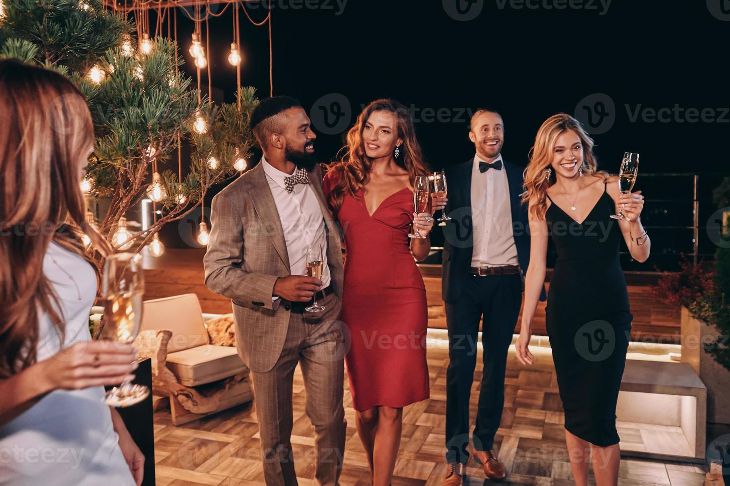 Group of beautiful people in formalwear communicating and smiling while spending time on luxury party photo