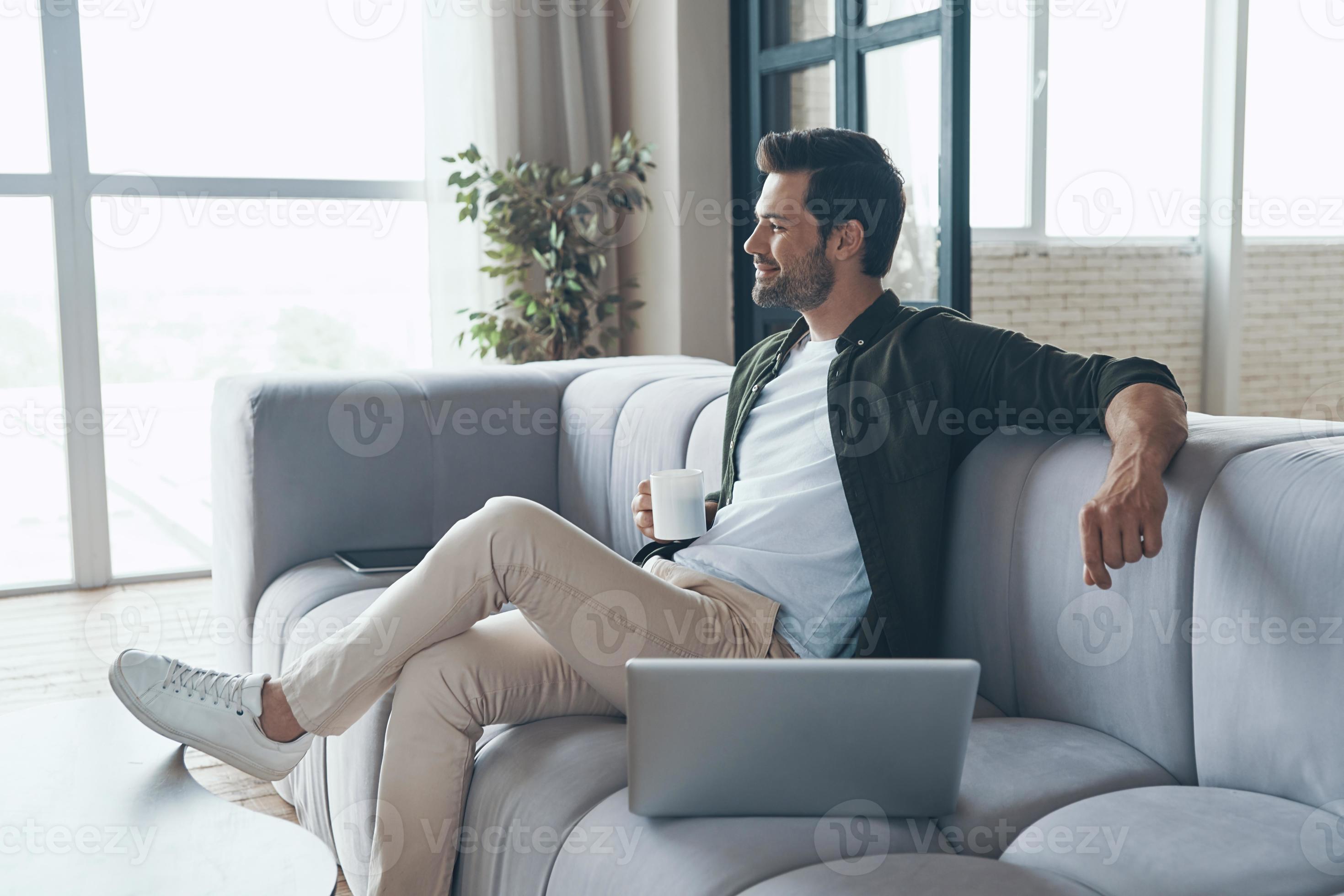 Thoughtful young man drinking coffee and looking away while sitting on