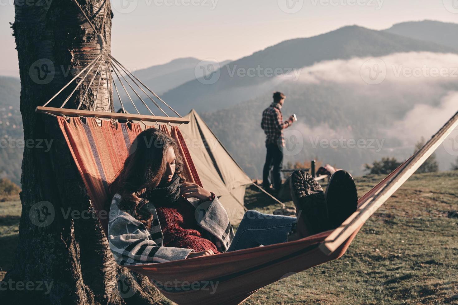 Feeling comfortable. Attractive young woman lying in hammock while camping with her boyfriend photo