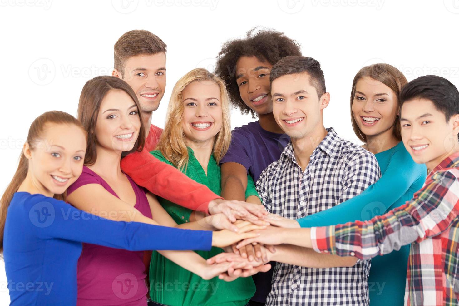 We are strong when we together. Cheerful group of multi-ethnic people holding hands together and smiling at camera while standing isolated on white photo