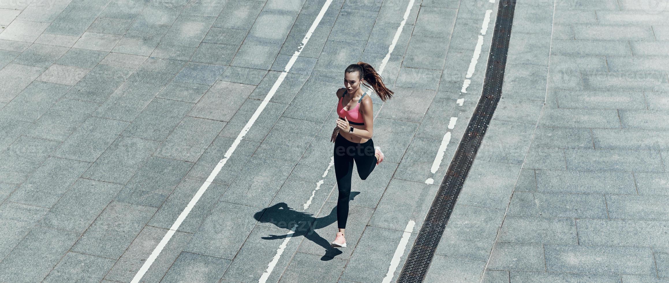 vista superior de una hermosa joven con ropa deportiva corriendo al aire libre foto