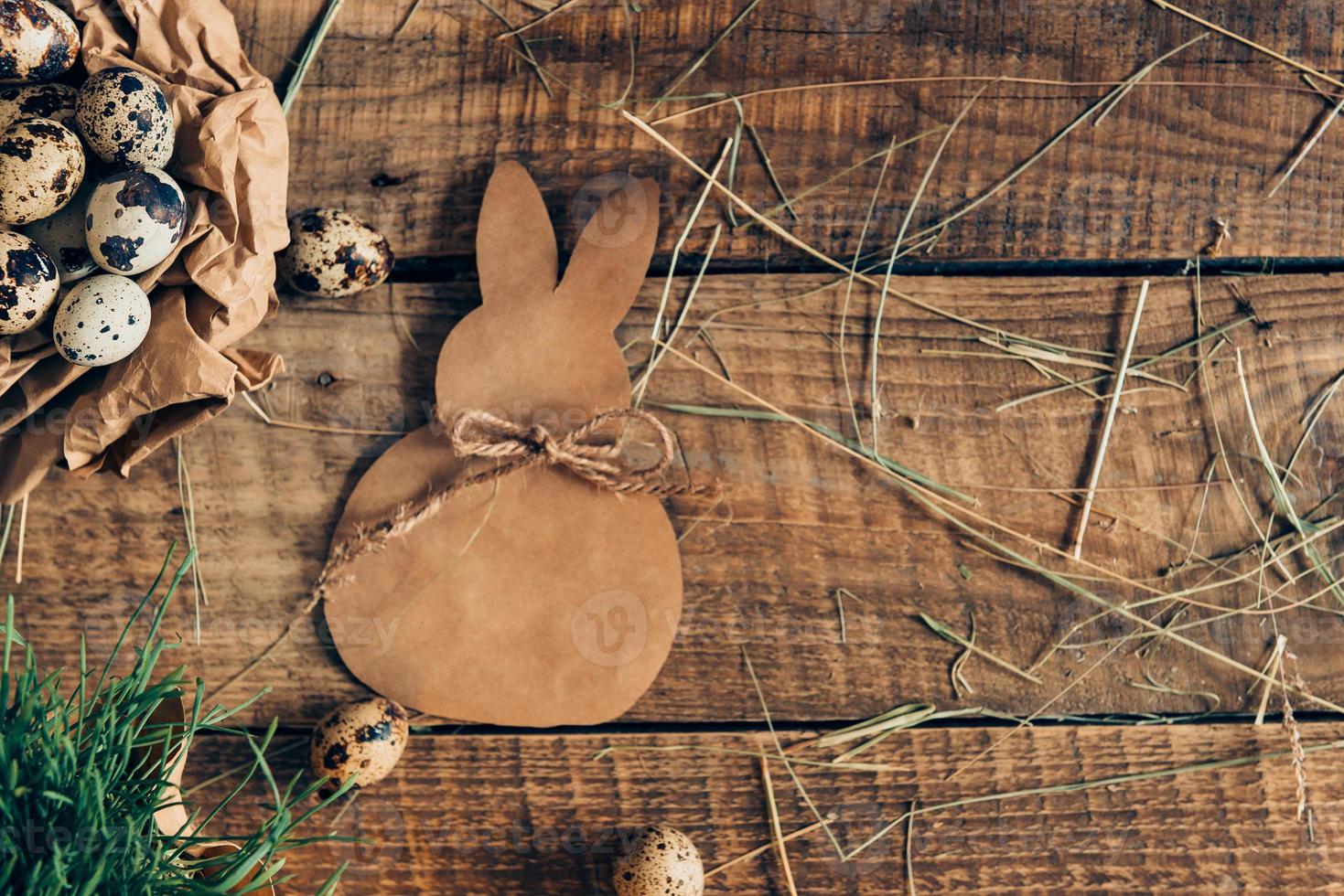 Organic Easter. Top view of quail eggs in crumpled brown paper and ester bunny lying on wooden rustic table photo