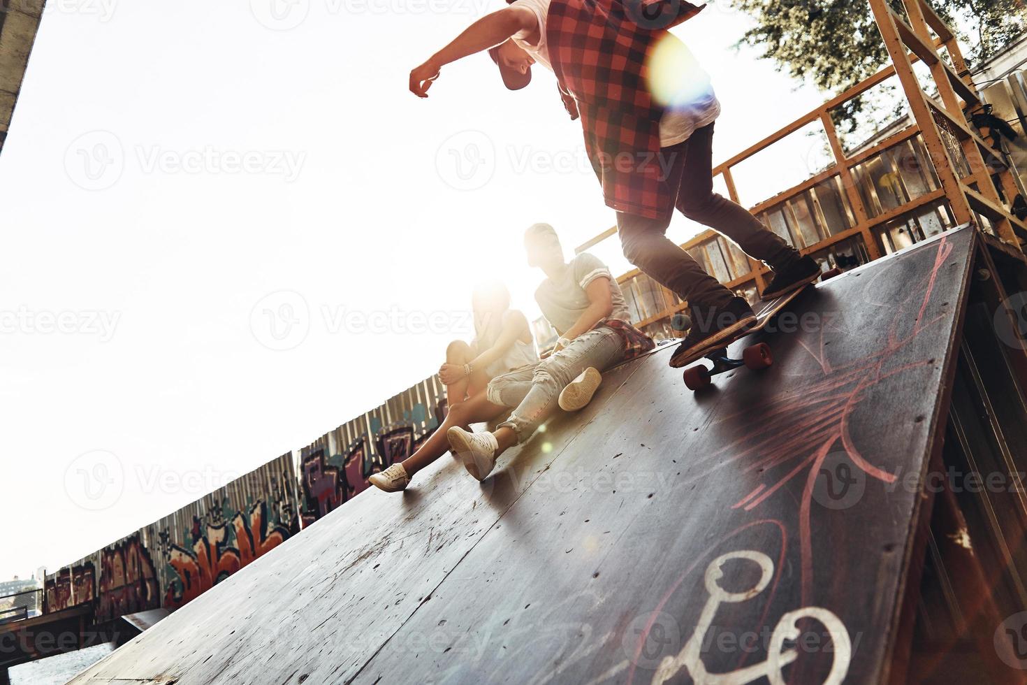 Feels like flying. Modern young men skateboarding while hanging out with his friends outdoors photo