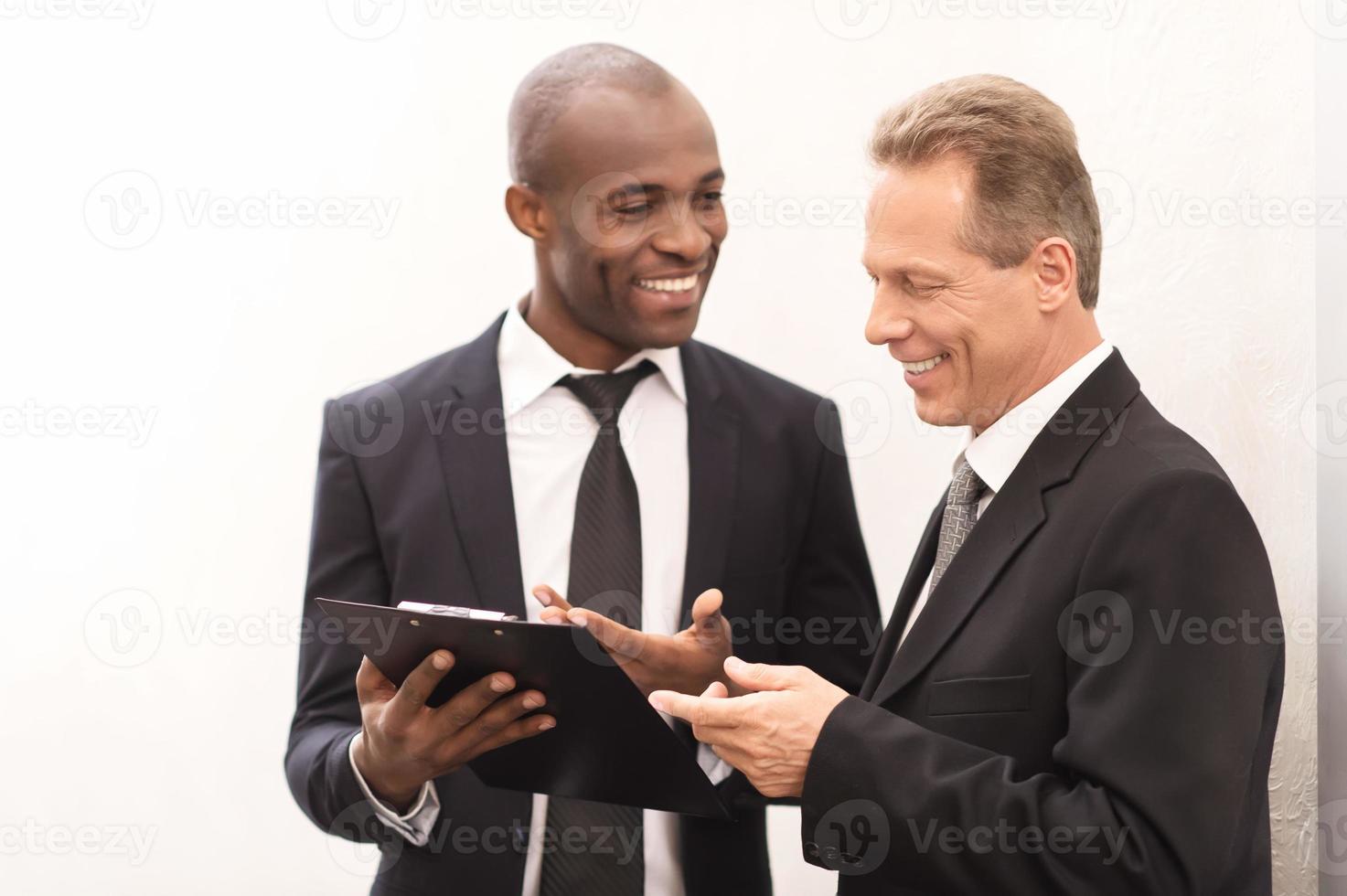 Discussing a new project. Two cheerful business men looking at the note pad and gesturing photo