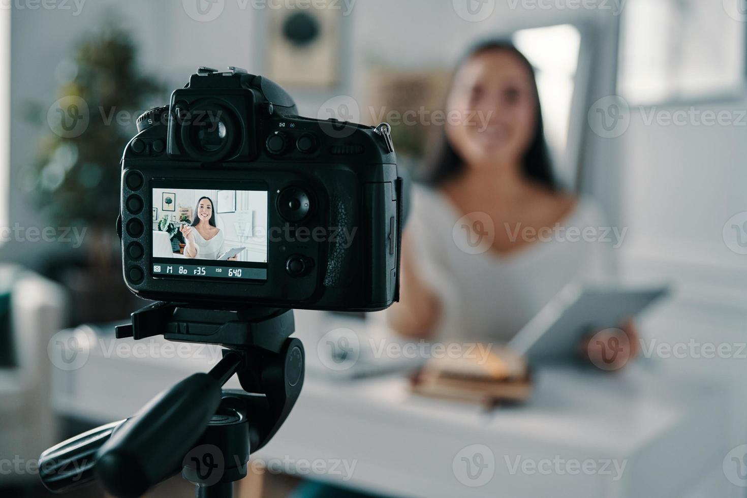 Blogging is her life. Beautiful young woman gesturing and smiling while making new video for her blog photo