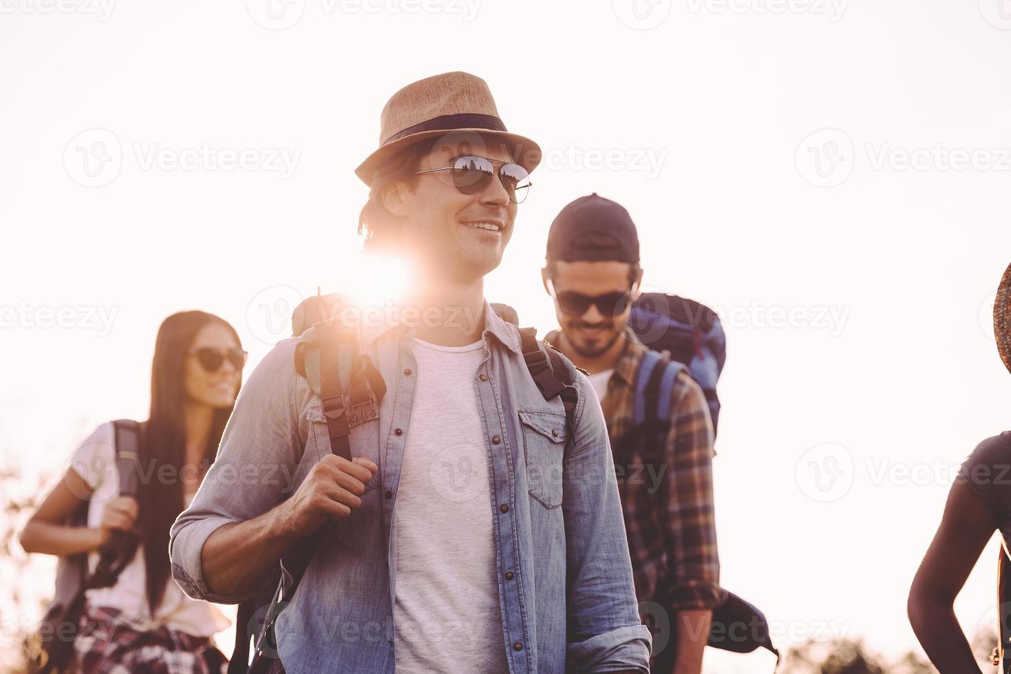 Friends hiking. Group of young people with backpacks walking together and looking happy photo