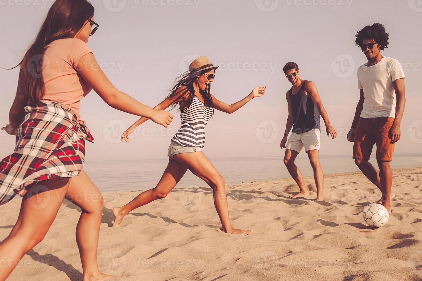 It is mine Group of cheerful young people playing with soccer ball on the beach with sea in the background photo
