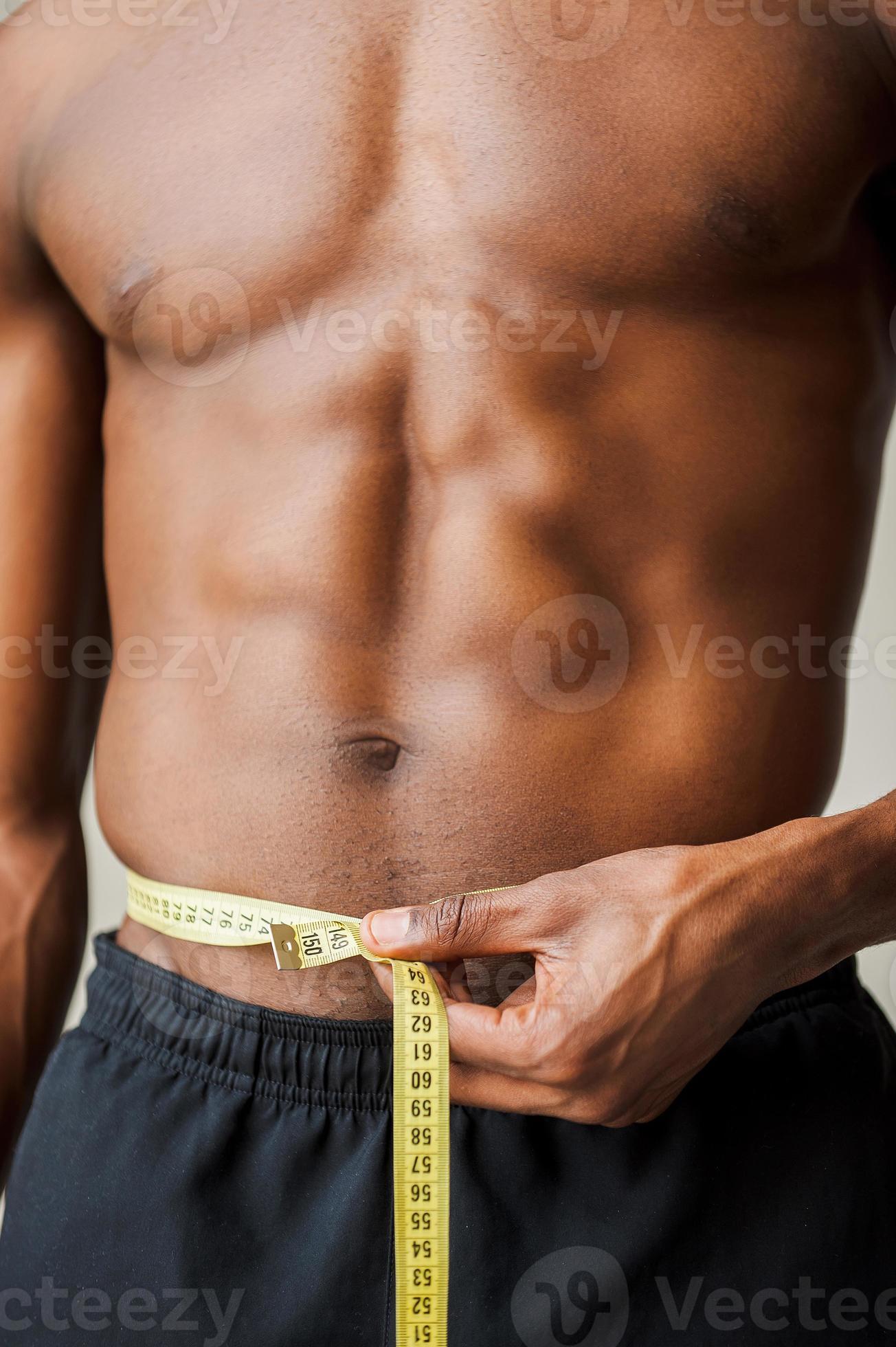 Closeup of bodybuilder holding tape measure. Cropped image of muscular arm  holding measuring tape isolated over gray background. Wrong muscle measuring.  Photos