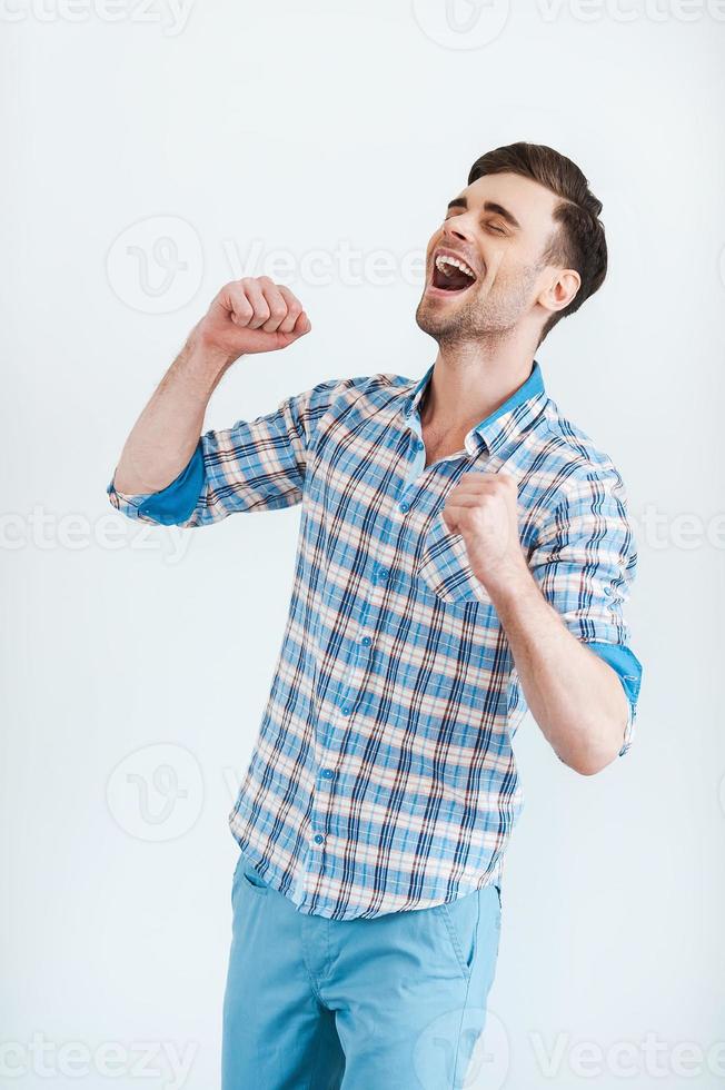 Happiness without limits. Cheerful young man in shirt gesturing and smiling while standing against white background photo