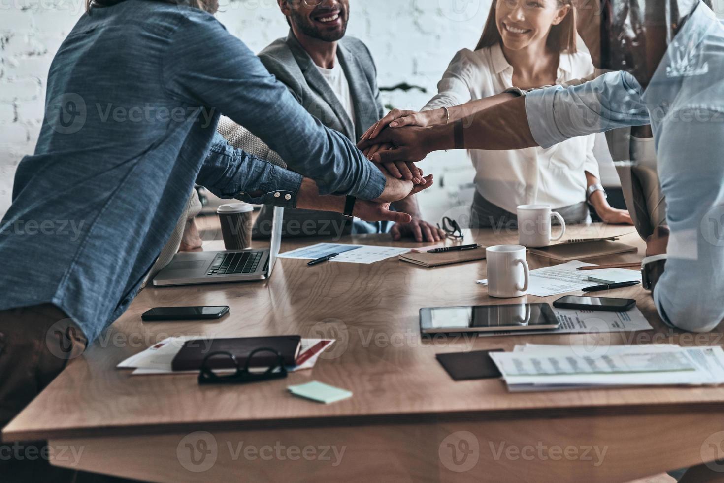 equipo exitoso cierre de un grupo diverso de colegas de negocios tomados de la mano uno encima del otro en un símbolo de unidad mientras trabajan en la sala de juntas foto