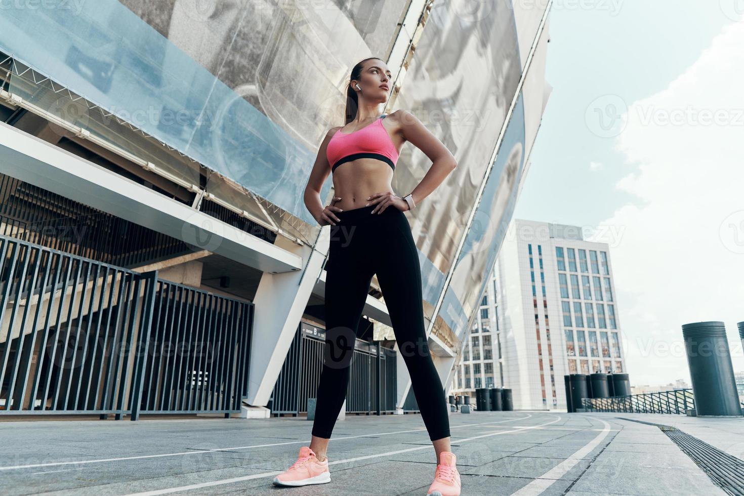 Full length of confident young woman in sportswear holding hands on hip photo