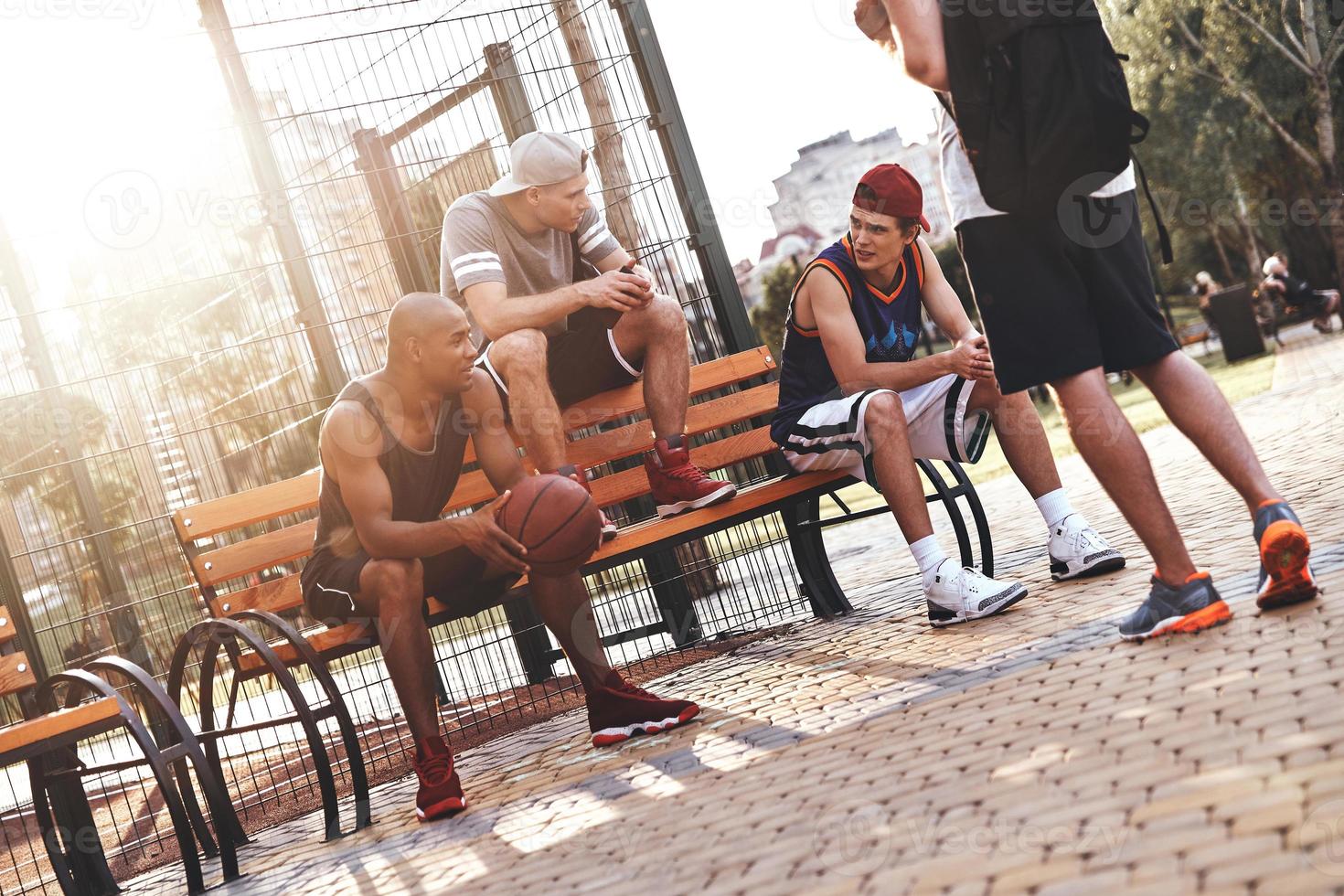 Weekend activities. Group of young men in sports clothing talking while spending time outdoors photo
