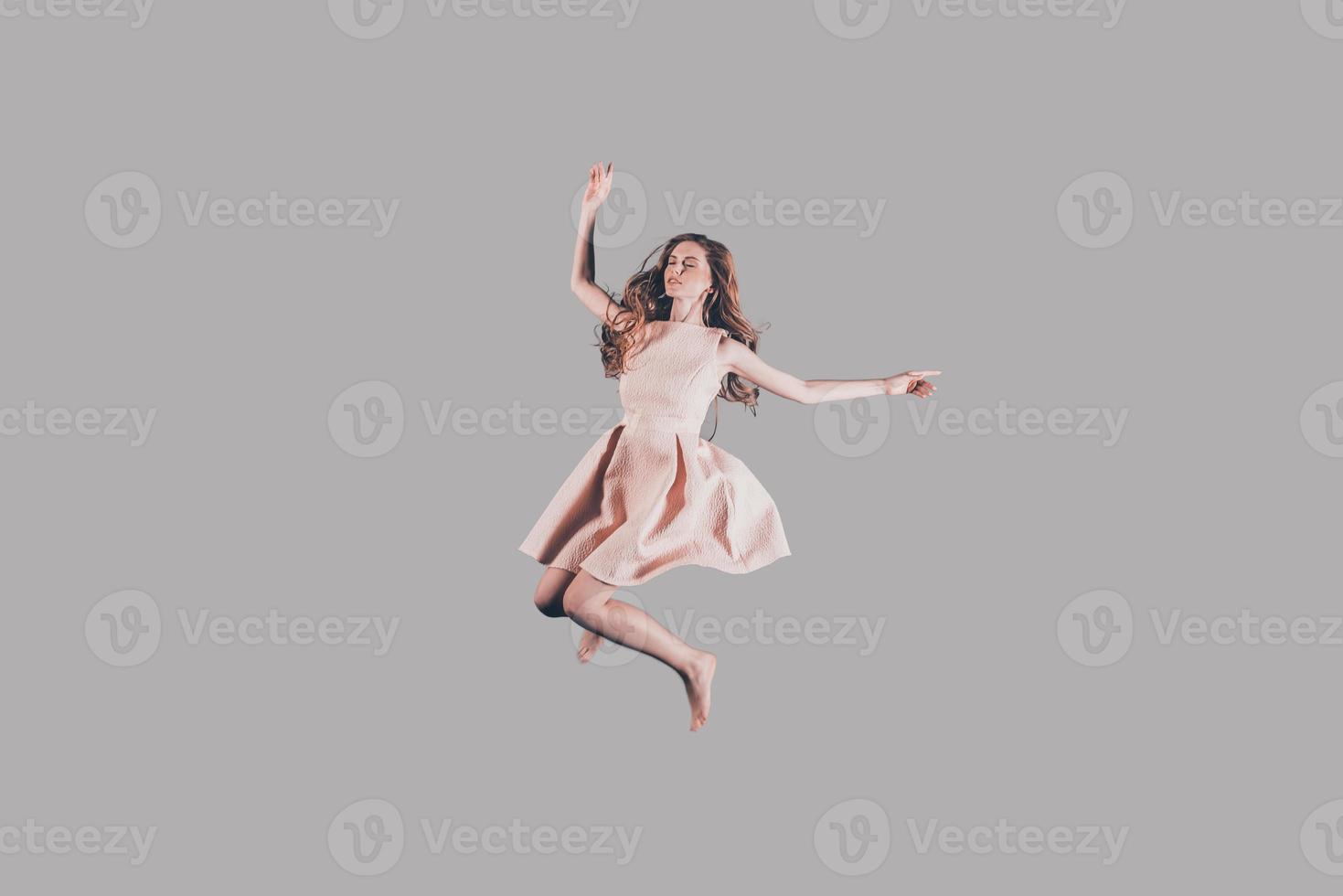 Beauty in motion. Studio shot of attractive young woman hovering in air photo