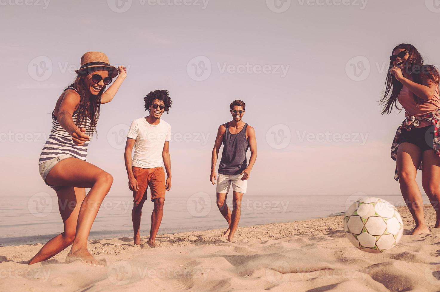 diversión en la playa grupo de jóvenes alegres jugando con una pelota de fútbol en la playa foto