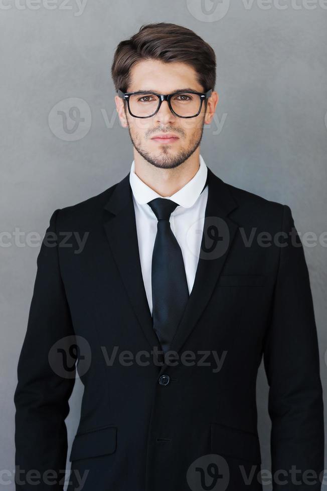 Confident and successful. Confident young man in formalwear looking at camera while standing against grey background photo