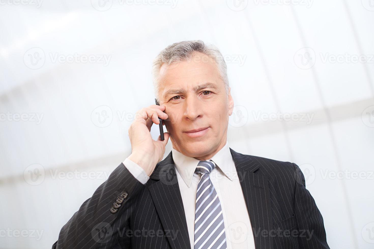 Businessman on the phone. Confident senior man in formalwear talking on the mobile phone and looking at camera photo