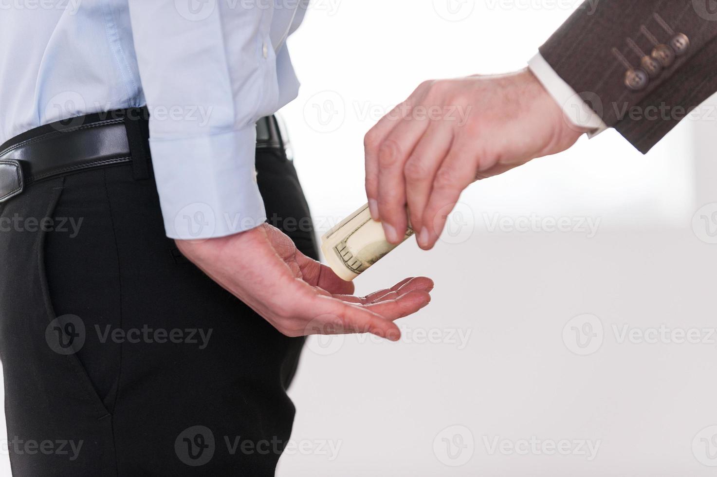 Giving a bribe. Close-up of businessman giving money to another man in formalwear photo
