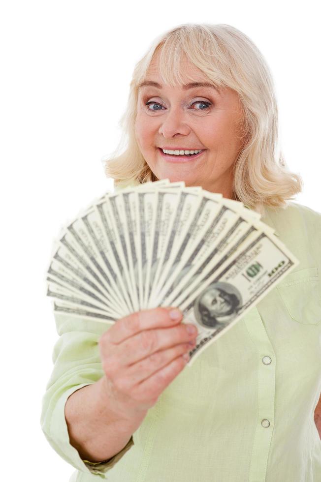 Savings. Happy senior woman stretching out hand with paper currency while standing isolated on white background photo