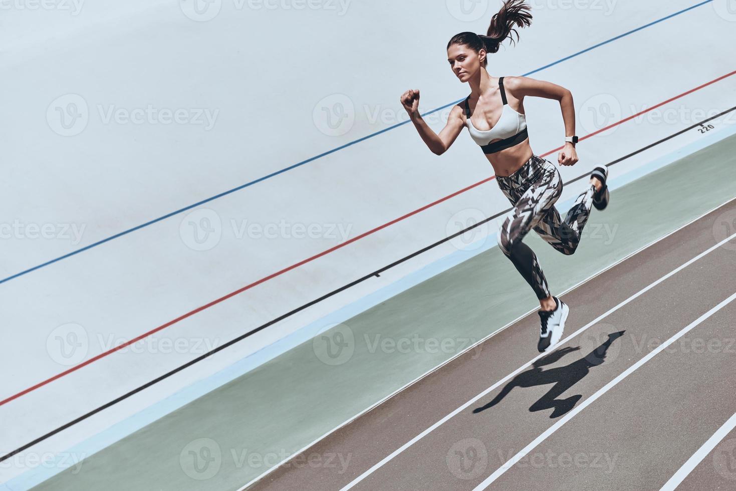 Always in shape. Top view of young woman in sports clothing jumping while exercising outdoors photo