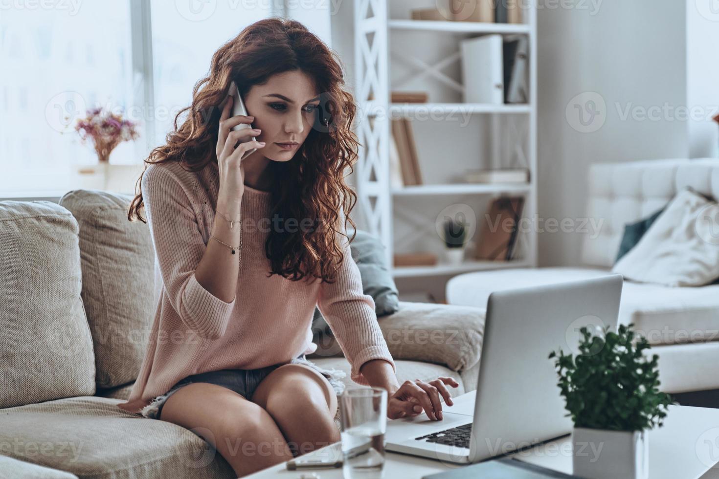 Need a doctor. Sick young women talking on smart phone and using computer while sitting on the sofa at home photo