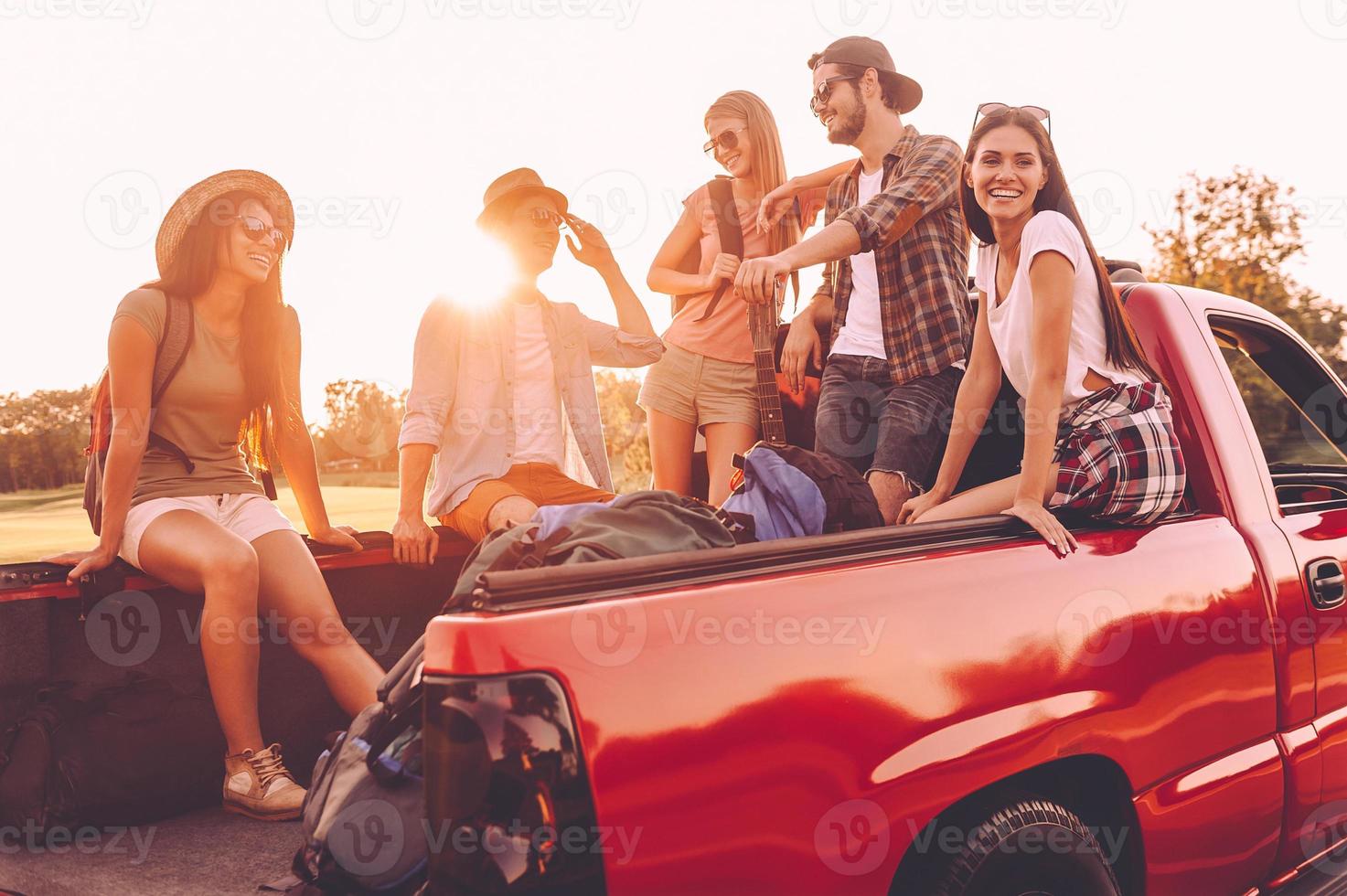 Ready to go. Group of young cheerful people sitting in pick-up truck and looking happy photo