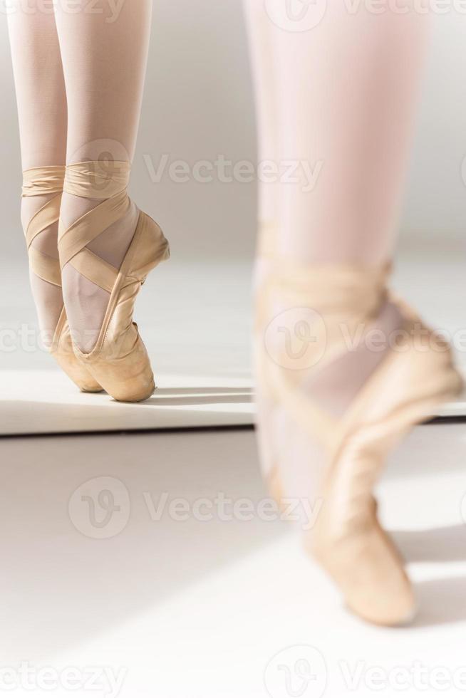 Grace and perfection. Close-up of ballerina legs in slippers standing against mirror photo