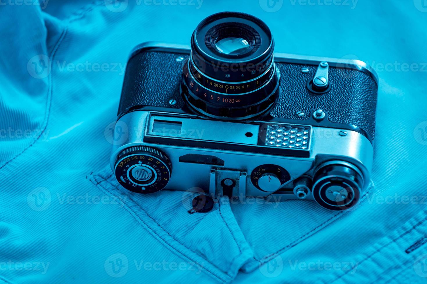 Retro styled camera. Close-up of retro camera laying on blue shirt photo