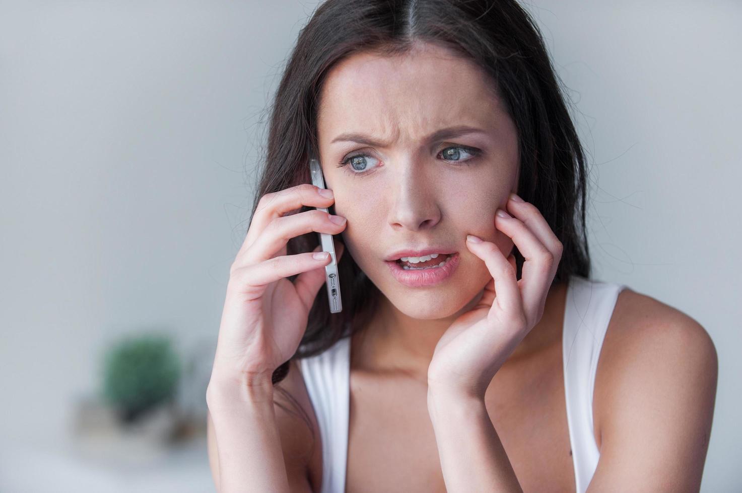 Depressed woman. Depressed young women talking on mobile phone sitting in bed photo