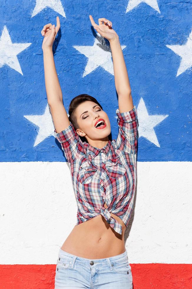 Happy winner. Happy young short hair woman holding arms raised while standing against American flag background photo
