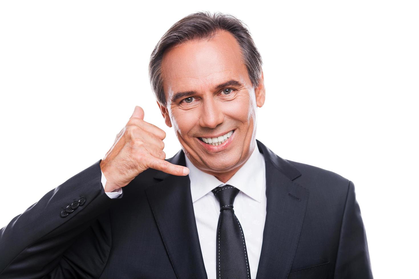 Waiting for your call. Happy mature man in formalwear gesturing mobile phone near his face and smiling while standing isolated on white background photo