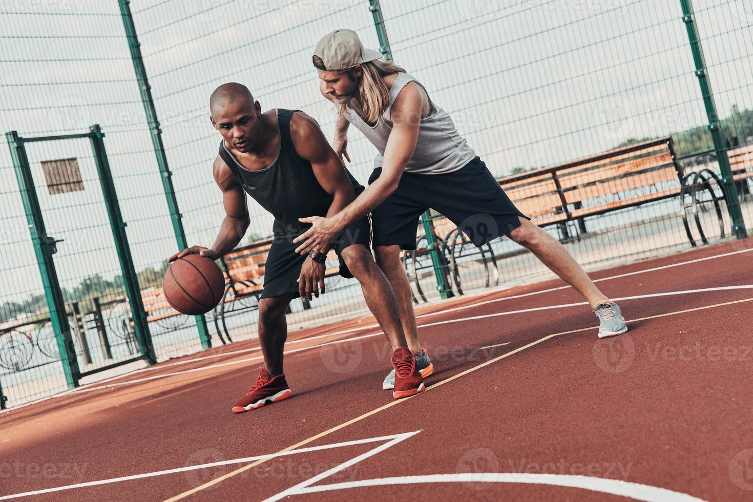 Jugando difícil. dos jóvenes con ropa deportiva jugando baloncesto mientras pasan tiempo al aire libre foto