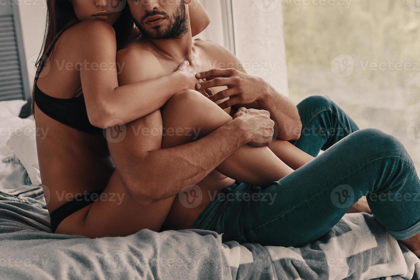 Quite moments together. Beautiful young semi-dressed couple embracing while spending time in the bedroom photo