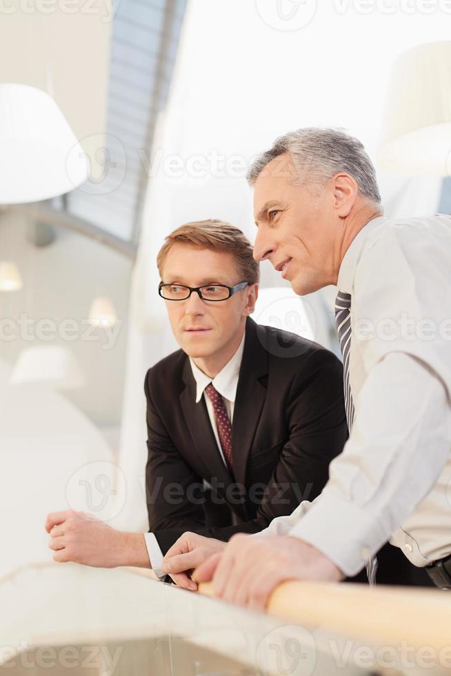 Discussing business. Two confident business men discussing something while holding papers in their hands photo