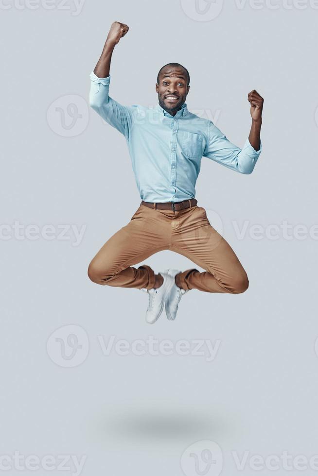 Playful young African man gesturing and shouting while hovering against grey background photo