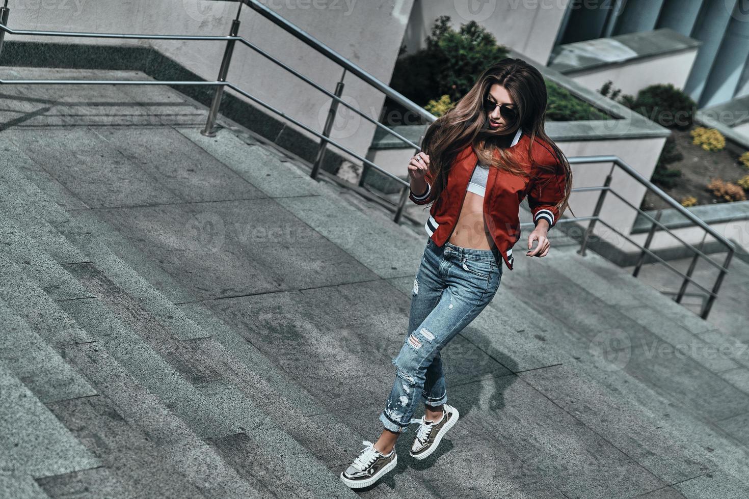 On the way to success. Full length of beautiful young woman in casual wear running up the stairs while spending time outdoors photo