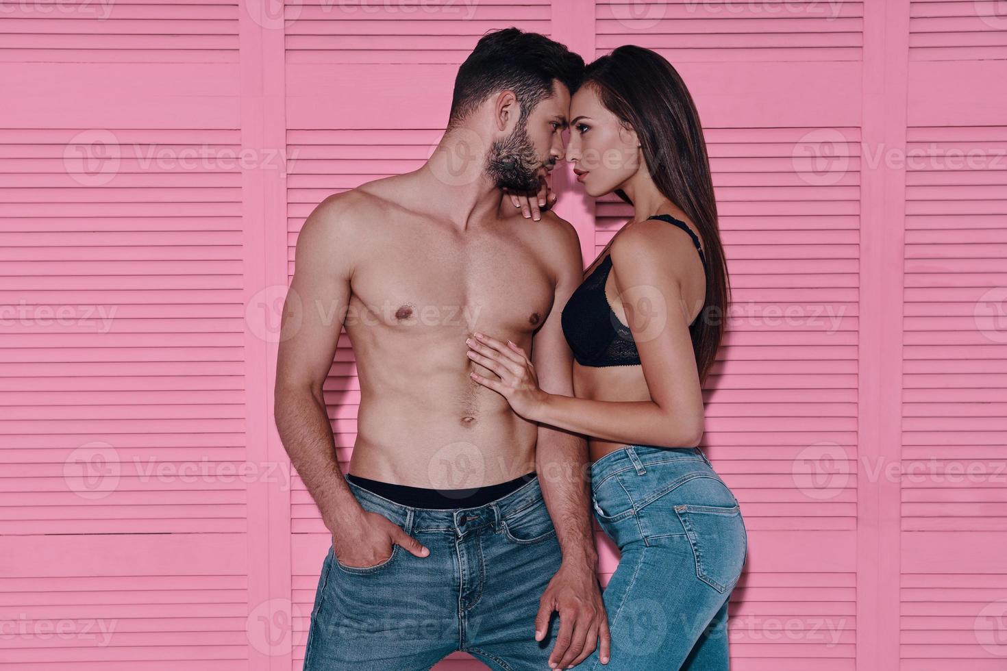 Love is in the air. Beautiful young couple bonding face to face while standing against pink background photo