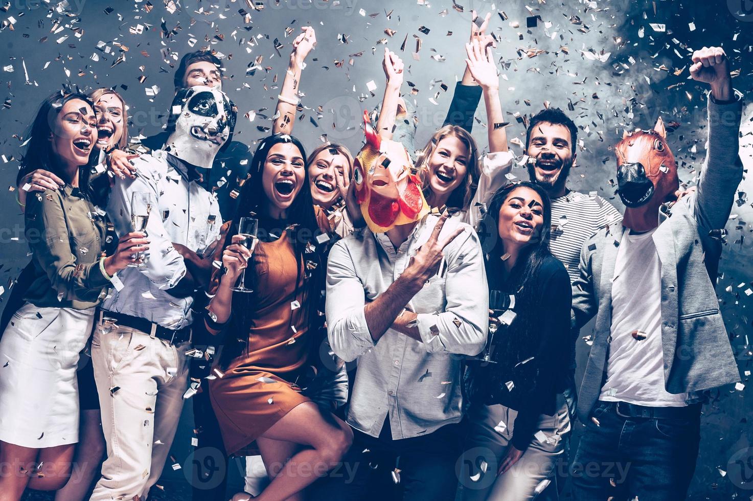 Year of rooster. Group of young people in animal masks throwing confetti and looking happy photo